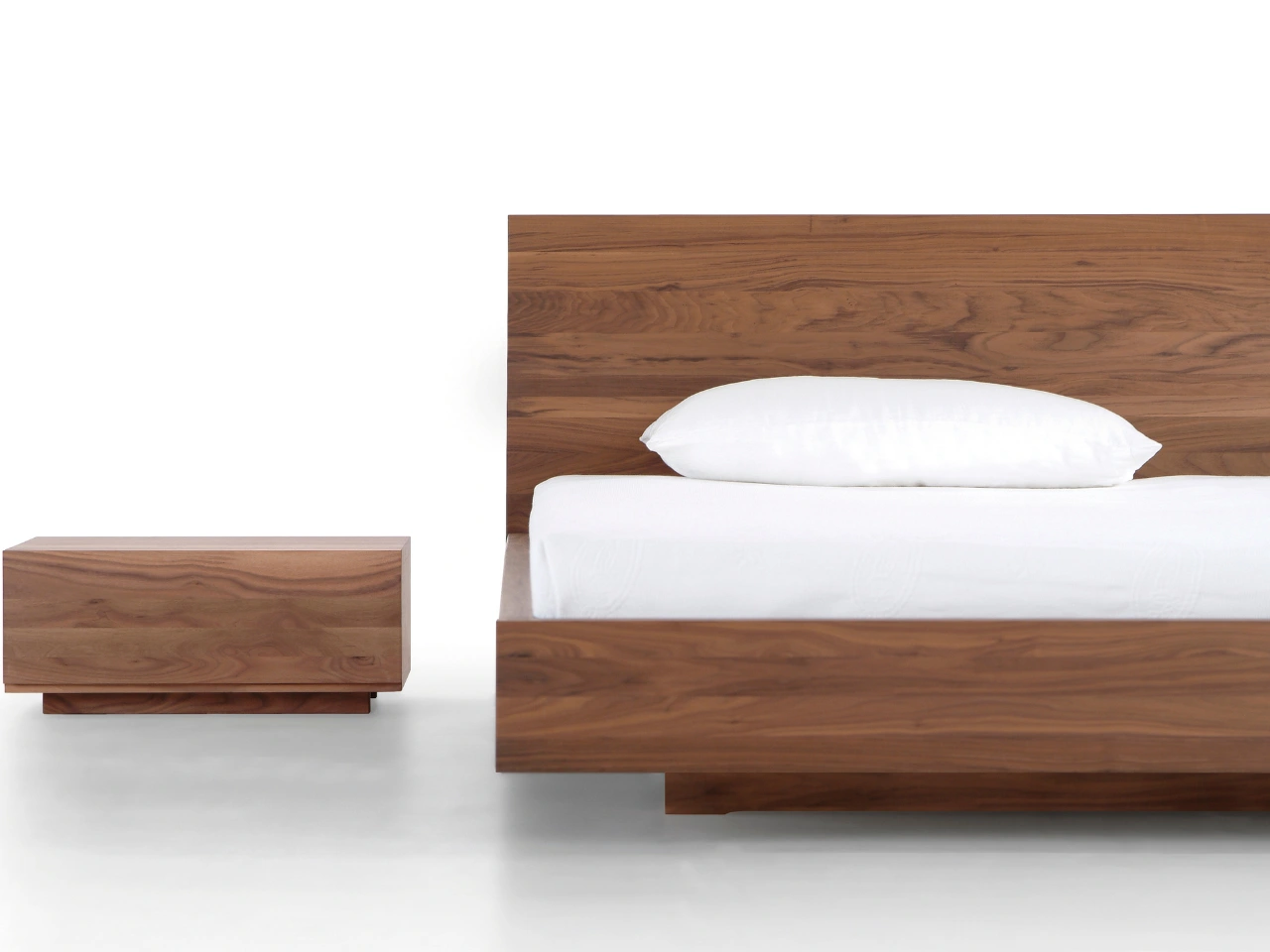 Massivholzbett aus Nussbaum mit puristischem Nachttisch im gleichen Holzton