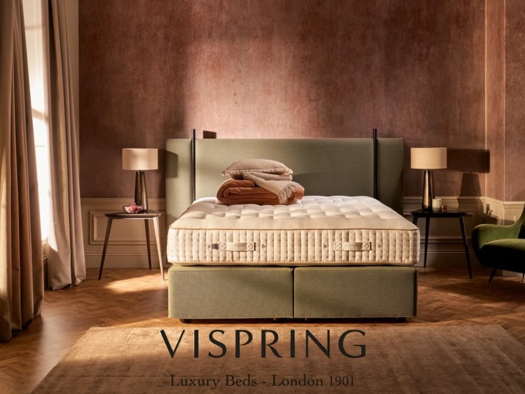 Grünes Boxspringbett in hellem Raum mit Holzfußboden